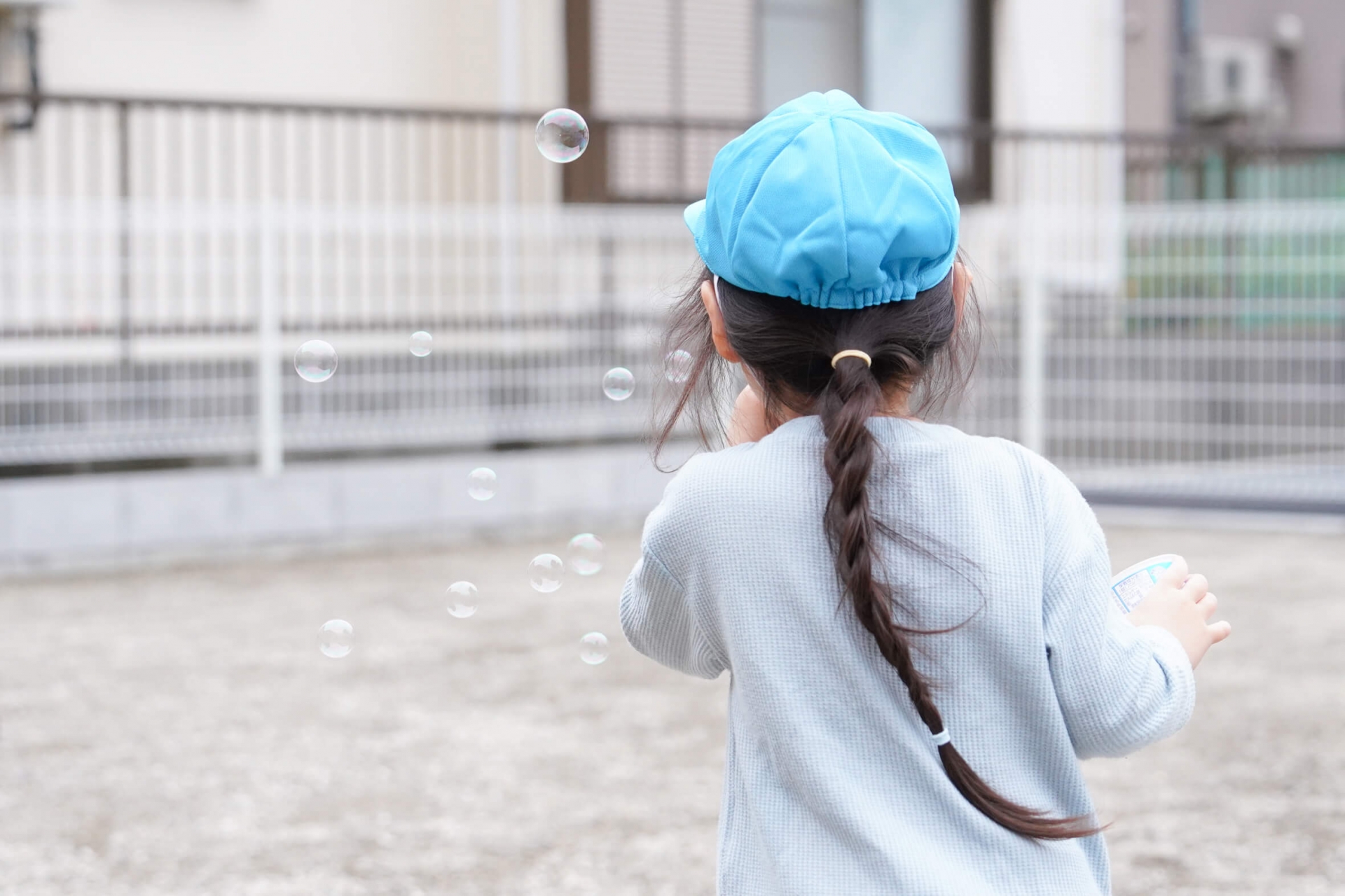 シャボン玉を吹く子どもの後ろ姿